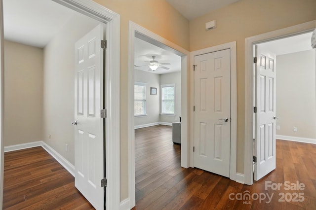 hallway with dark wood-type flooring and baseboards