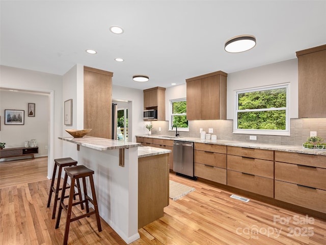 16 Emerson Poore Dr, Candler, NC 28715 - kitchen featuring appliances with stainless steel finishes, a breakfast bar area, backsplash, a peninsula, and light wood-style flooring