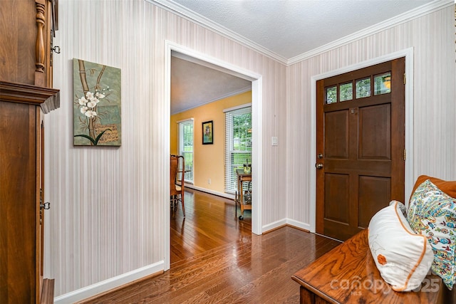 foyer entrance with dark wood-style flooring, crown molding, baseboards, and wallpapered walls