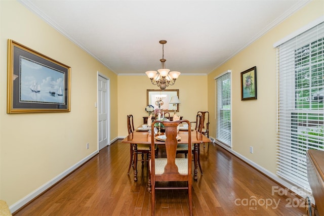 dining area featuring a chandelier, wood finished floors, crown molding, and baseboards