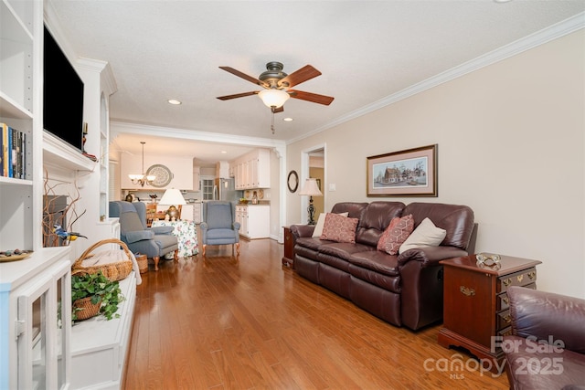 living area with a ceiling fan, light wood-style flooring, crown molding, a chandelier, and recessed lighting