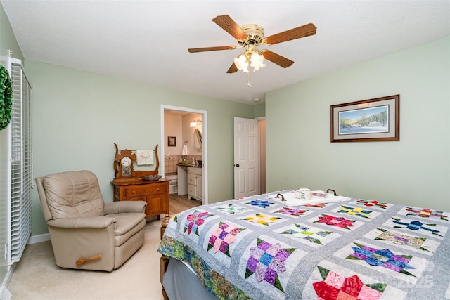 bedroom with light colored carpet, ensuite bathroom, and a ceiling fan