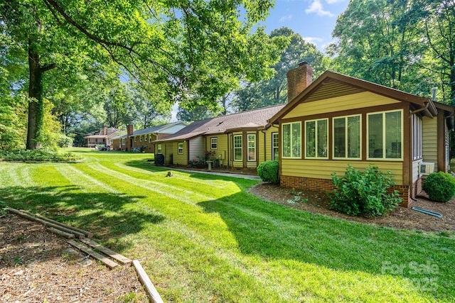 rear view of property with a chimney and a lawn