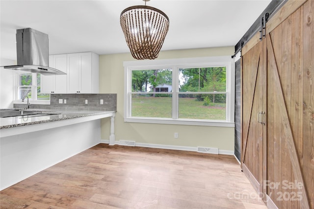 1501 E Church St, Cherryville, NC 28021 - kitchen featuring island exhaust hood, light wood finished floors, decorative backsplash, light stone countertops, and white cabinetry