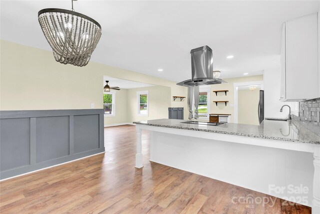 1501 E Church St, Cherryville, NC 28021 - kitchen with island exhaust hood, light stone countertops, white cabinetry, open floor plan, and light wood-type flooring