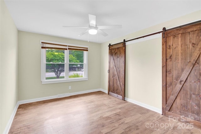 1501 E Church St, Cherryville, NC 28021 - unfurnished bedroom with a barn door, wood finished floors, baseboards, and a ceiling fan