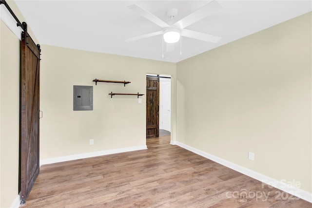 1501 E Church St, Cherryville, NC 28021 - empty room with a barn door, electric panel, light wood-type flooring, baseboards, and a ceiling fan