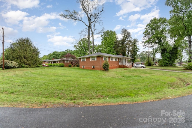 view of side of property with a chimney, a yard, and brick siding