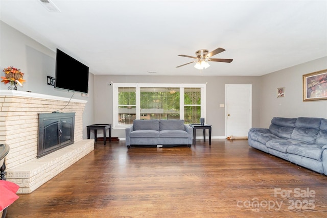 living room with a ceiling fan, wood finished floors, a fireplace, and baseboards