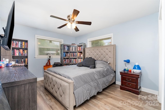 bedroom featuring multiple windows, wood finished floors, baseboards, and a ceiling fan