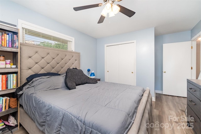 bedroom with wood finished floors, a closet, baseboards, and a ceiling fan