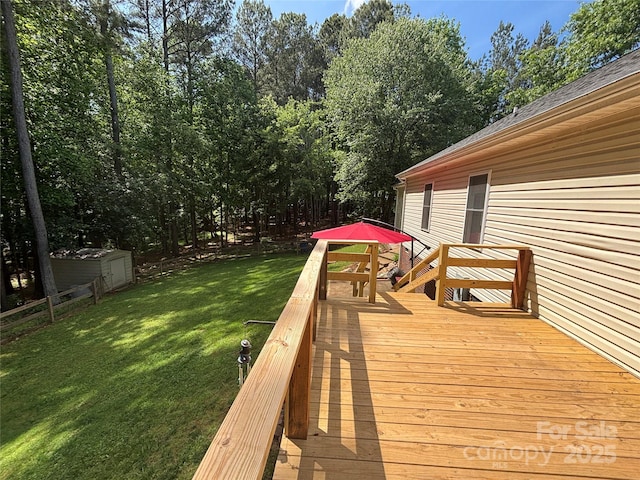 wooden deck featuring a lawn, a storage unit, an outbuilding, and view of wooded area