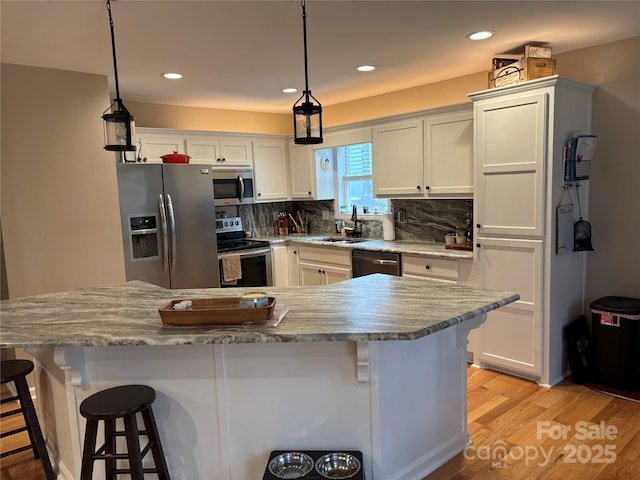 kitchen featuring stainless steel appliances, a sink, white cabinetry, a breakfast bar area, and recessed lighting