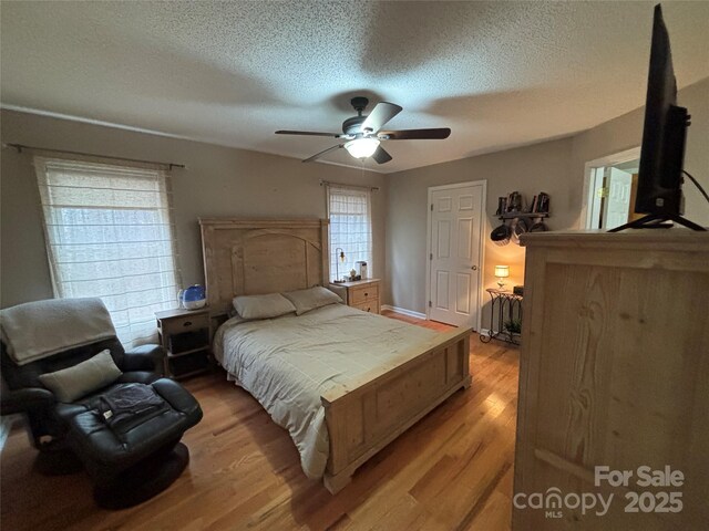 bedroom with light wood-style flooring, a textured ceiling, and a ceiling fan