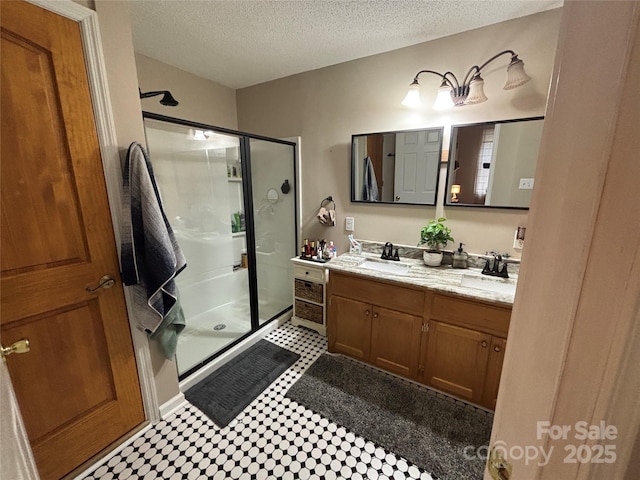 bathroom featuring tile patterned floors, a stall shower, a textured ceiling, and double vanity