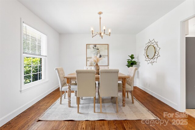 dining space with a chandelier, wood finished floors, and baseboards