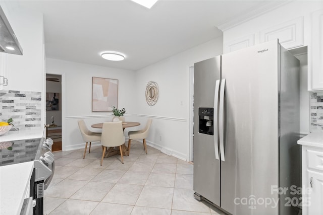 kitchen featuring stainless steel refrigerator with ice dispenser, light countertops, tasteful backsplash, light tile patterned floors, and white cabinetry