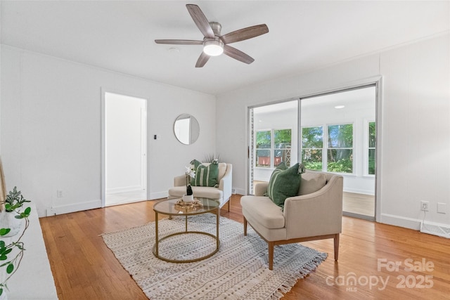 living room featuring light wood finished floors, ceiling fan, and baseboards