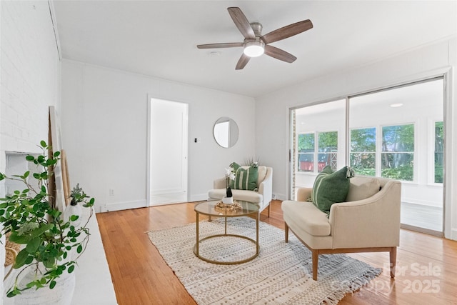 living area with light wood-style flooring, ceiling fan, and baseboards