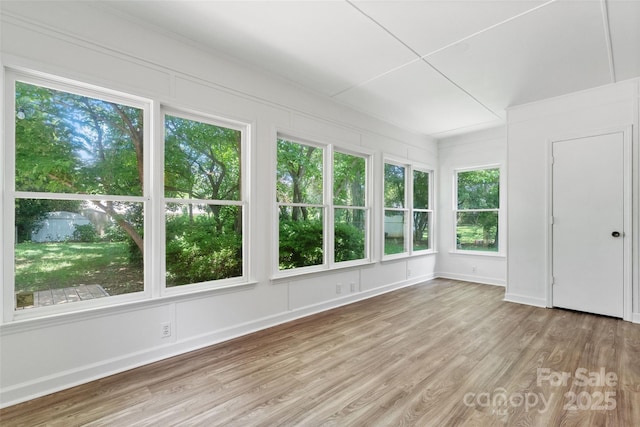 unfurnished sunroom featuring wood finished floors, baseboards, and a wooden deck