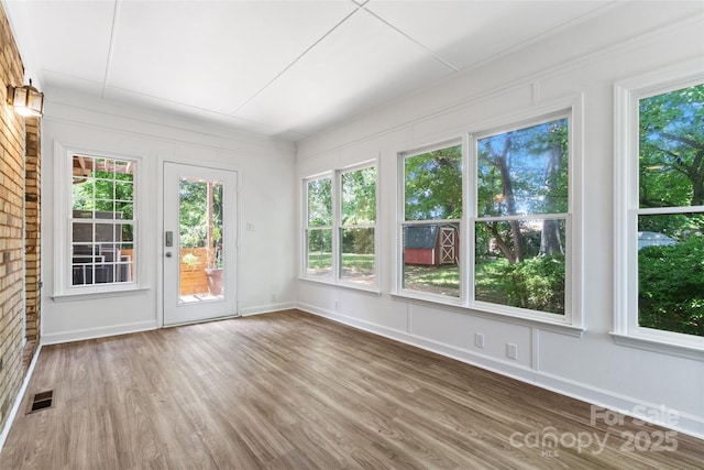 unfurnished sunroom featuring wood finished floors, healthy amount of natural light, and baseboards