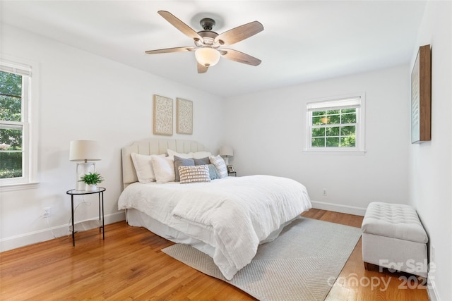 bedroom featuring baseboards, light wood-type flooring, and ceiling fan