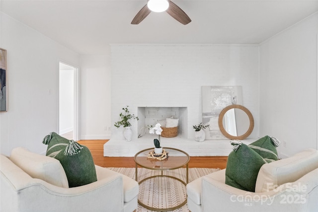 sitting room featuring ceiling fan, wood finished floors, and a fireplace