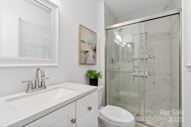 bathroom featuring a marble finish shower, toilet, and vanity