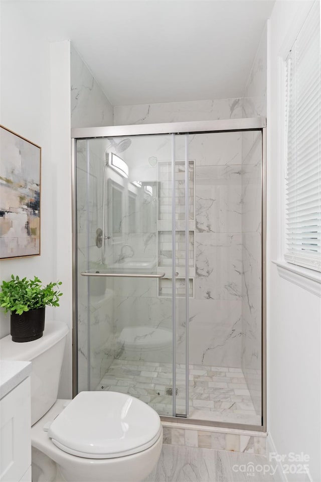 bathroom with marble look tiles, toilet, a marble finish shower, and vanity