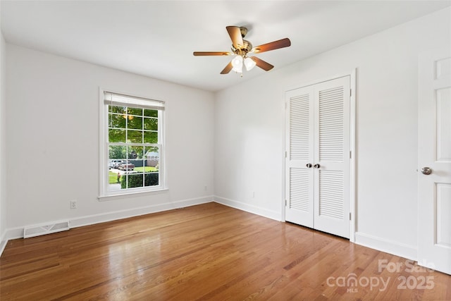unfurnished bedroom featuring wood finished floors, baseboards, and a closet