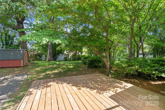wooden terrace with a shed, an outdoor structure, and a lawn