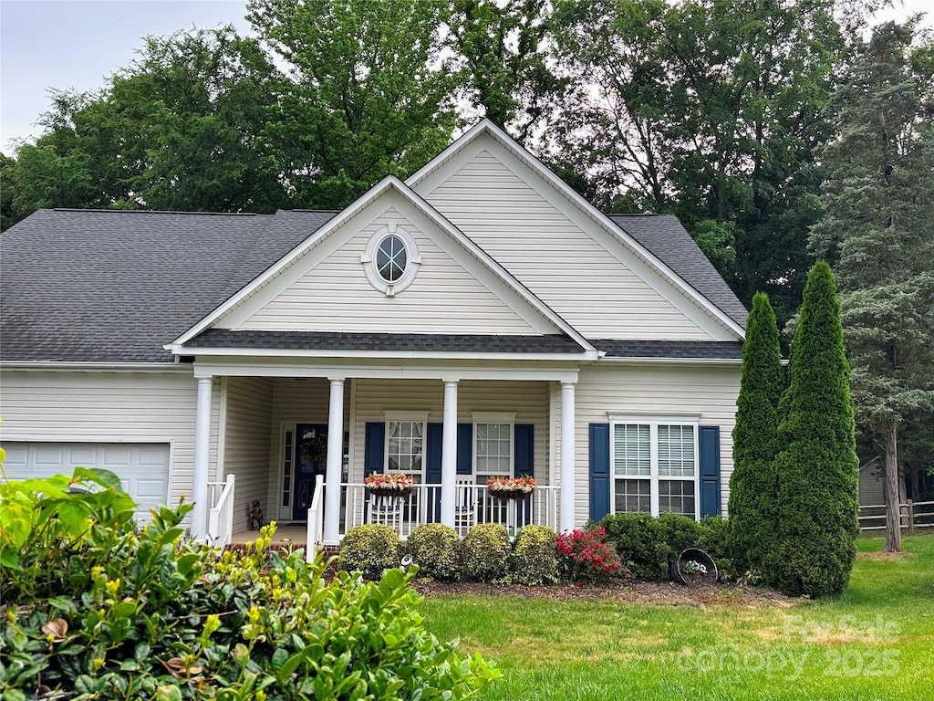 neoclassical / greek revival house with covered porch, an attached garage, a shingled roof, and a front lawn