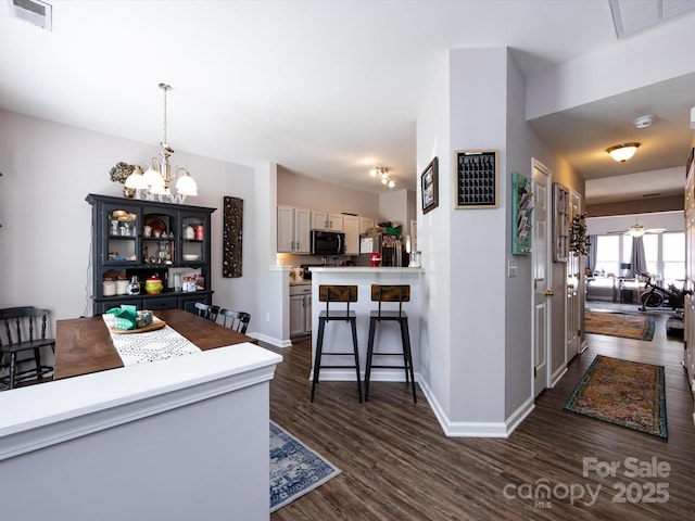 kitchen with black microwave, a chandelier, dark wood finished floors, and baseboards