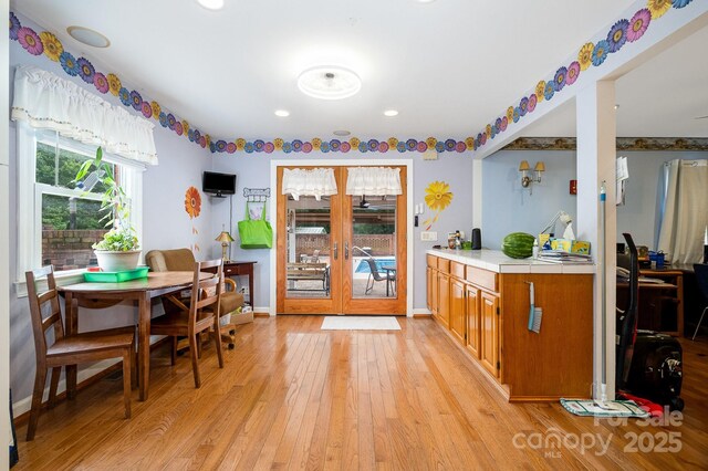 907 Sikes Mill Rd, Monroe, NC 28110 - kitchen with light wood finished floors, french doors, brown cabinetry, tile countertops, and recessed lighting