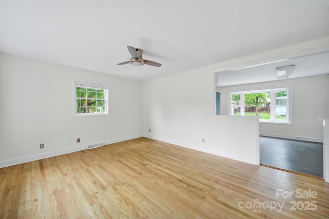 unfurnished room featuring healthy amount of natural light, wood finished floors, a ceiling fan, and baseboards