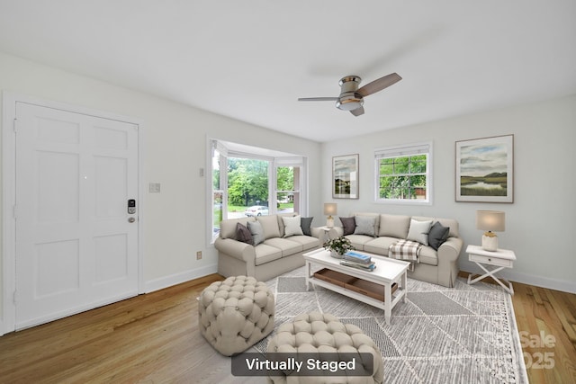 living room featuring plenty of natural light, wood finished floors, a ceiling fan, and baseboards