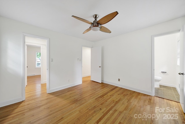 unfurnished bedroom featuring light wood-type flooring, baseboards, ensuite bath, and ceiling fan