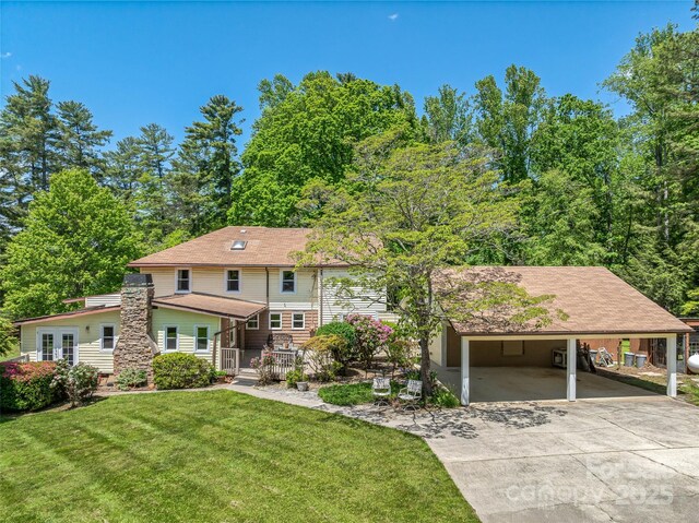 view of front of property featuring concrete driveway, a carport, and a front yard