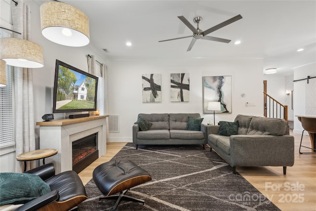 324 Elm St, Belmont, NC 28012 - living area with wood finished floors, a ceiling fan, recessed lighting, a barn door, and a glass covered fireplace