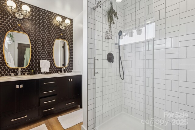 324 Elm St, Belmont, NC 28012 - full bathroom with a tile shower, wood finished floors, double vanity, and backsplash