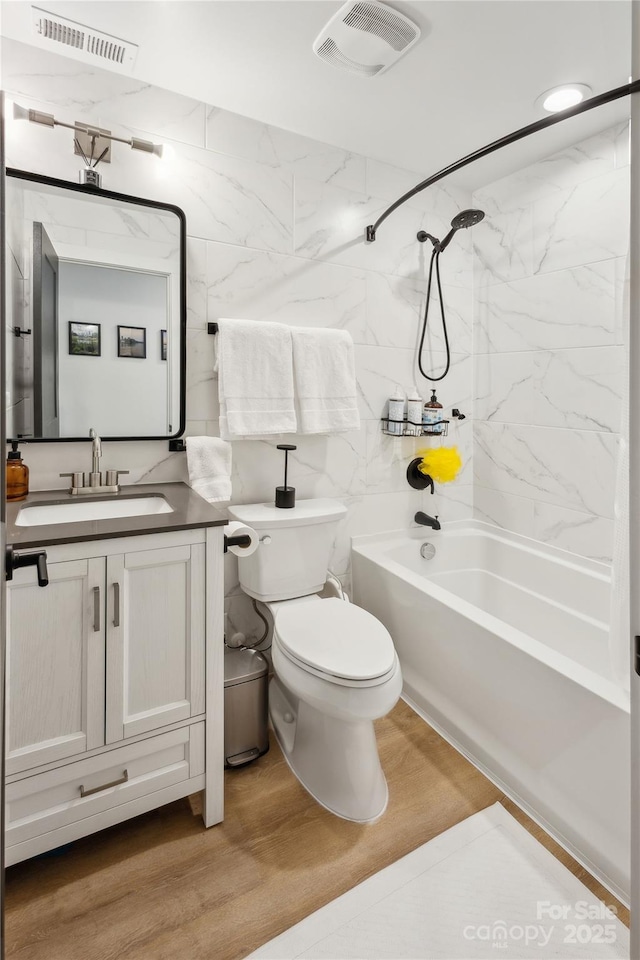 324 Elm St, Belmont, NC 28012 - bathroom featuring wood finished floors, toilet, shower / washtub combination, vanity, and tile walls
