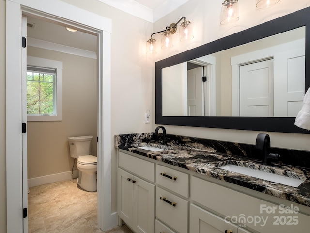 full bathroom featuring toilet, baseboards, double vanity, and crown molding