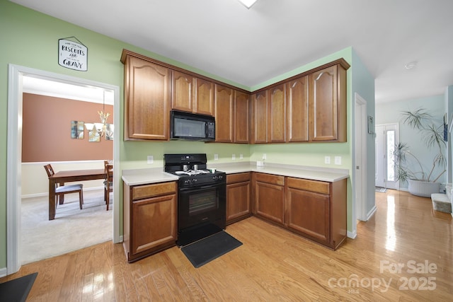 2017 White Cedar Ln, Waxhaw, NC 28173 - kitchen with black appliances, light countertops, light wood-type flooring, brown cabinetry, and baseboards
