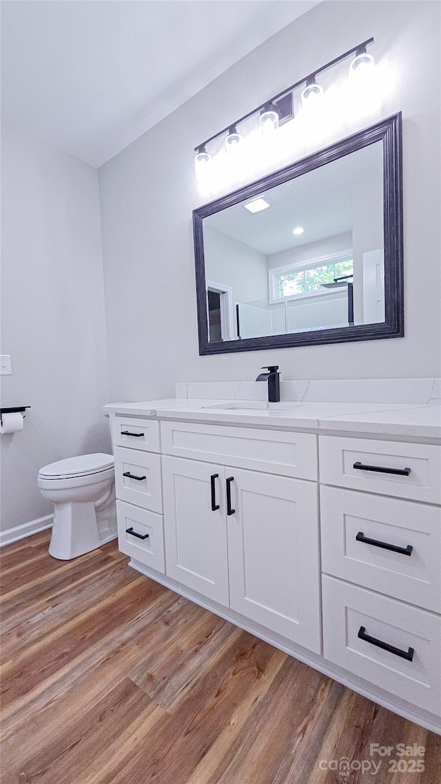 bathroom with toilet, wood finished floors, and vanity