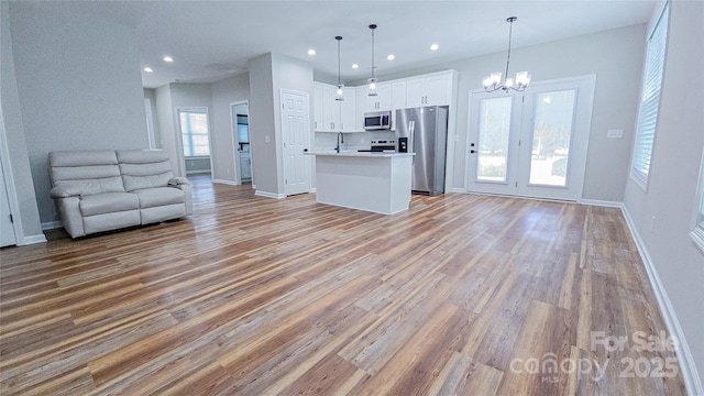 unfurnished living room with a chandelier, light wood-style floors, baseboards, a sink, and recessed lighting