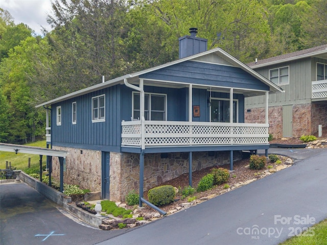 336 Stoney Ridge Loop, Maggie Valley, NC 28751 - view of front facade with board and batten siding, stone siding, a chimney, and a wooded view