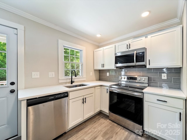 83 Woodsdale Pl SE, Concord, NC 28025 - kitchen featuring appliances with stainless steel finishes, a sink, light wood finished floors, crown molding, and decorative backsplash