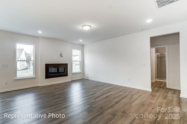 8619 Frank Grier Rd Unit 3, Charlotte, NC 28215 - unfurnished living room featuring healthy amount of natural light, dark wood-style flooring, a glass covered fireplace, baseboards, and recessed lighting