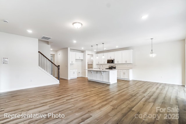 8619 Frank Grier Rd Unit 3, Charlotte, NC 28215 - unfurnished living room featuring a sink, light wood-style floors, recessed lighting, stairway, and baseboards