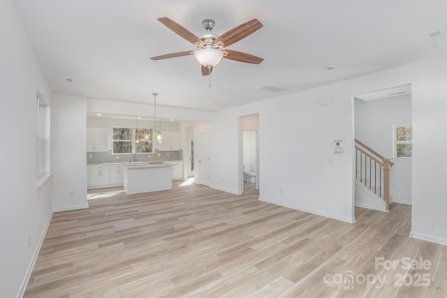 318 Sixth St, Belmont, NC 28012 - unfurnished living room with stairs, light wood-style flooring, a ceiling fan, baseboards, and a sink